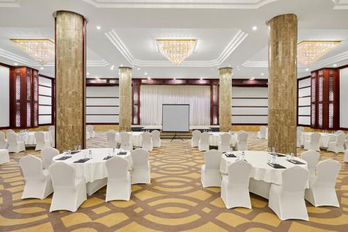 a banquet hall with white tables and chairs and a screen at Makarem Mina Hotel in Makkah