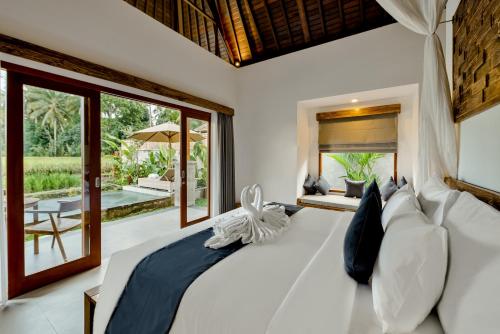 Poka Villa & Spa في أوبود: غرفة نوم بسرير كبير ومخدات بيضاء
