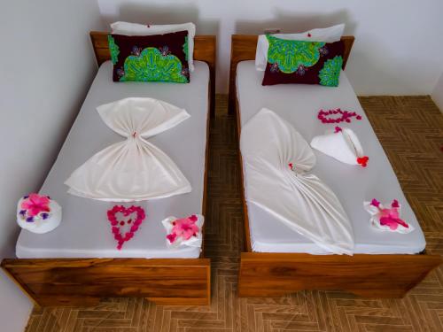 - 2 lits avec des draps blancs et des fleurs dans l'établissement Bella Vista Resort Zanzibar, à Kizimkazi