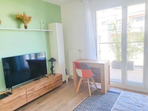a living room with a television and a desk with a chair at EXIGEHOME-Bel appartement de standing-30 minutes de Paris in Vélizy-Villacoublay