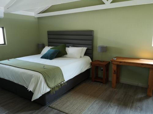 a bedroom with a large bed and a wooden desk at Crimson Bush Lodge in Klipdrift
