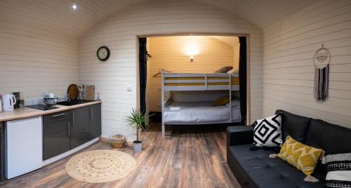 a living room with a couch and a kitchen and a bunk bed at The Buzzard - 6 Person Family Glamping Cabin in Dungarvan