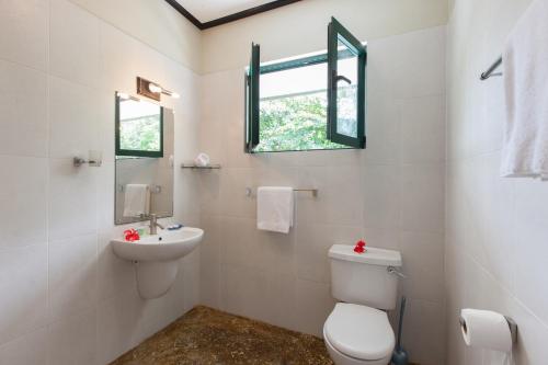 a white bathroom with a toilet and a sink at La Kaz Safran in La Digue