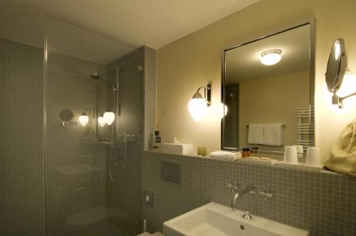 uma casa de banho com um chuveiro, um lavatório e um espelho. em Historisches Alpinhotel Grimsel Hospiz em Grimsel Hospiz