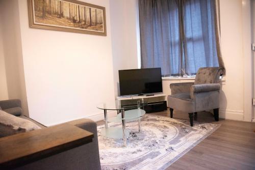 a living room with a tv and two chairs and a table at Coral Place in Luton