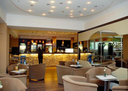 um restaurante com mesas e cadeiras e um bar em Sport Hotel em Debrecen