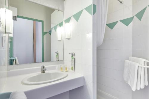 La salle de bains blanche est pourvue d'un lavabo et d'un miroir. dans l'établissement Club Vacances Bleues Les Horizons du Lac (anciennement Serre-du-Villard), à Chorges