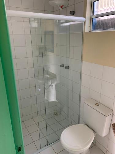 a bathroom with a toilet and a glass shower at Suítes Maresias in São Sebastião