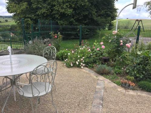 une table et des chaises dans un jardin fleuri dans l'établissement Petite maison de caractère, à Parey-sous-Montfort