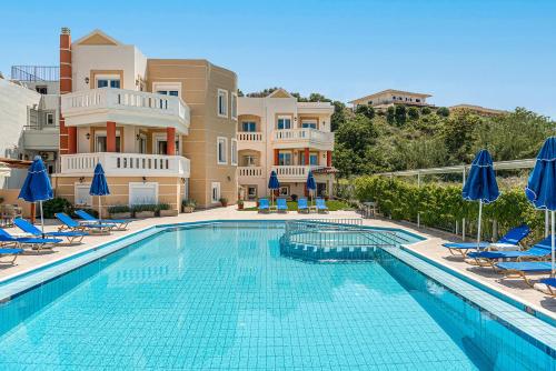a swimming pool with chairs and umbrellas in front of a building at Artemis Apartments in Stalos