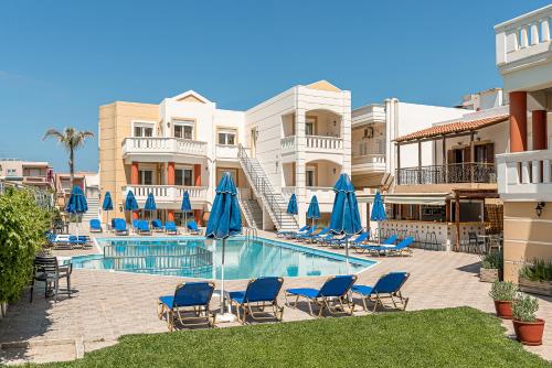a swimming pool with blue chairs and umbrellas at Artemis Apartments in Stalos