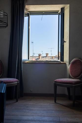 a room with two chairs and a large window at Casa Mustiola in Montalcino