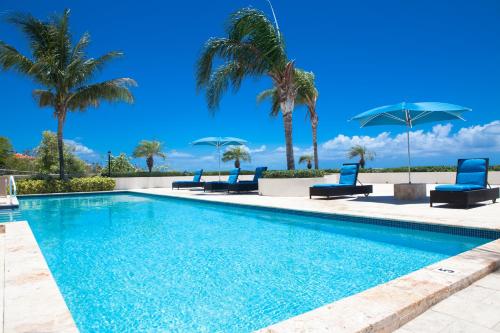 uma piscina com cadeiras azuis e palmeiras em La Vista Azul - Lovely Spacious Condo close to Grace Bay - Free Wi-Fi em Turtle Cove