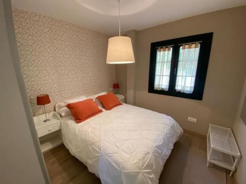 ein Schlafzimmer mit einem Bett mit zwei orangenen Kissen darauf in der Unterkunft Casa en Montealegre reformada y acogedora (wifi) in Sámano