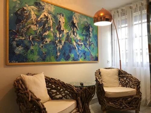 a painting hanging above two chairs and a table at Hôtel Le Neptune en Camargue in Saintes-Maries-de-la-Mer