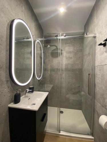 uma casa de banho com um chuveiro, um lavatório e um espelho. em Apartament La Playa! Najlepsza lokalizacja! em Hel