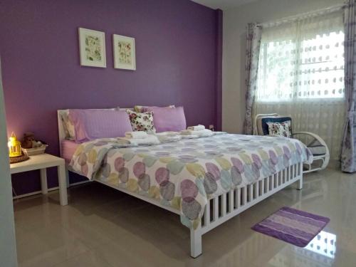 a bedroom with a bed and a purple wall at Better Weather Homestay in Pak Chong