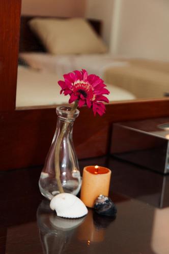 a vase with a flower and a candle on a table at Elaria Hotel Hurgada in Hurghada
