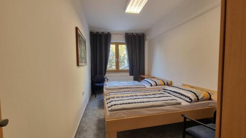 two beds in a room with a window at Hotel Rada in Ostrava