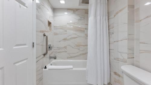 a white bathroom with a tub and a shower at La Mer Beachfront Resort in Cape May