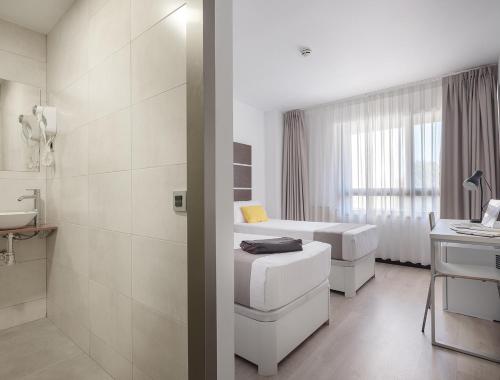 Baño blanco con 2 camas y lavamanos en Roisa Hostal Boutique, en Madrid