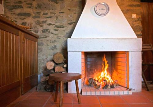 una chimenea con taburete y una mesa frente a ella en CASA VELHA, en Cernache do Bonjardim