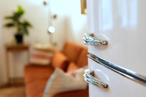 a white refrigerator in a living room with a couch at Stilvolles Apartment in zentraler Lage in Graz