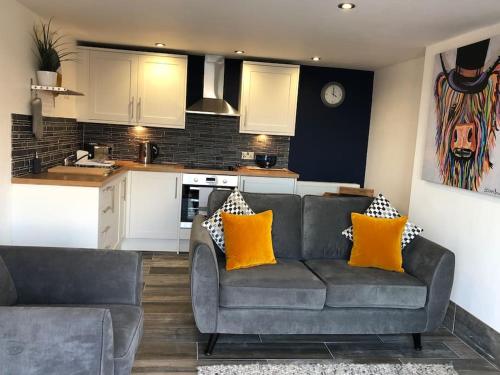 a living room with a couch and a kitchen at Mumbles - Modern Apartment with panoramic sea views in Oystermouth