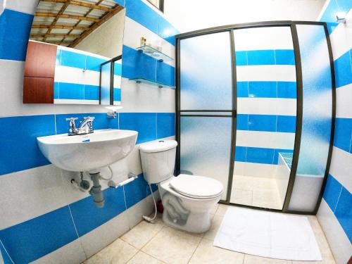 baño azul y blanco con aseo y lavamanos en Casa Flórez Hotel Campestre en Ibagué