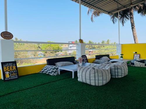 a group of chairs and tables on a green floor at Trippy Spot Hostel & Cafe in Vagator
