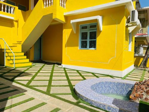 a yellow house with a courtyard in front of it at Trippy Spot Hostel & Cafe in Vagator