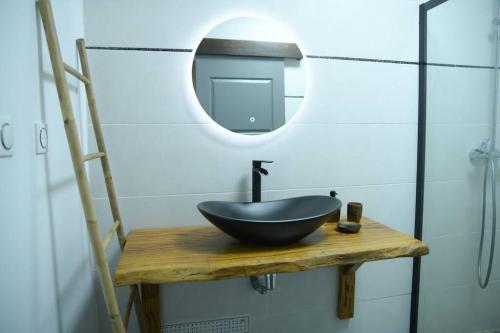 La salle de bains est pourvue d'un lavabo noir et d'un miroir. dans l'établissement Lodge Palmeraie & son Jacuzzi exclusif, à Matoury