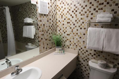 y baño con lavabo, aseo y espejo. en Stanford Inn & Suites, en Grande Prairie
