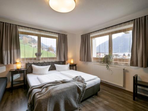 a bedroom with a large bed and two windows at Zillertal Suites in Kaltenbach