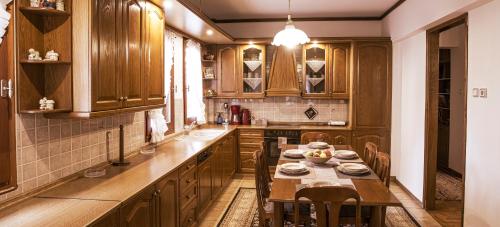 una cocina con armarios de madera y una mesa con sillas. en Georgia's GuestHouse, en Kastoria