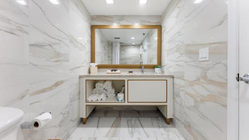 a bathroom with white marble walls and a vanity with a mirror at La Mer Beachfront Resort in Cape May
