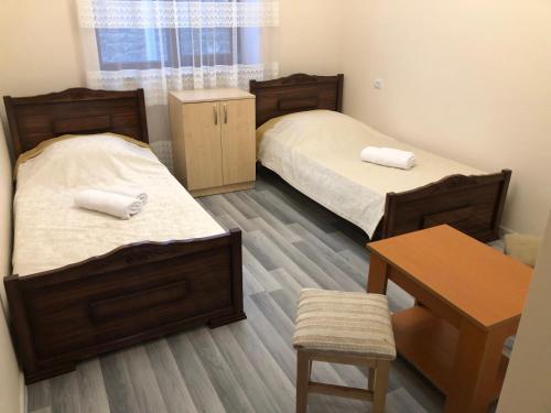 a room with two beds and a table and a desk at Liga Hotel and Restaurant in Shinuhayr