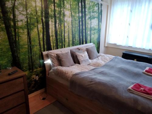 1 dormitorio con 1 cama con una pared de árboles en Szent Miklós Apartman en Hajdúszoboszló