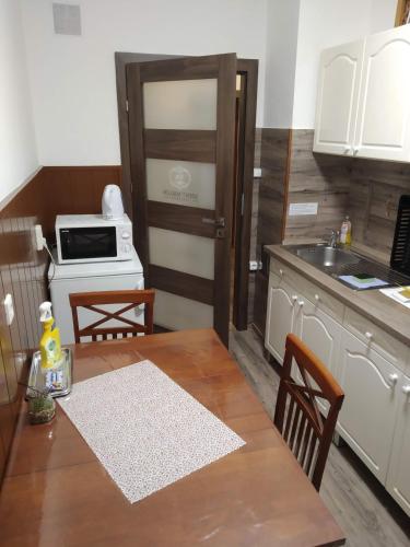 a kitchen with a wooden table and a kitchen with a sink at Szent Miklós Apartman in Hajdúszoboszló