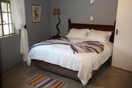 a bedroom with a bed with white sheets and a window at Kruger Ranch in Magaliesburg
