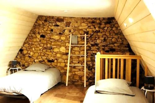 - une chambre avec un mur en pierre et 2 lits dans l'établissement LE MOULIN A VENT maison plein centre de SARLAT, à Sarlat-la-Canéda
