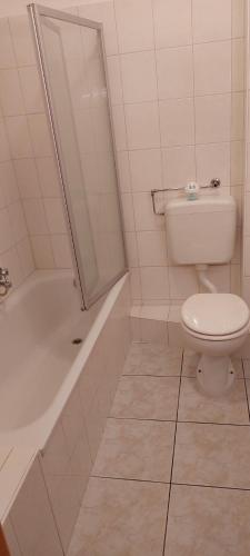La salle de bains blanche est pourvue de toilettes et d'une baignoire. dans l'établissement Ferienwohnung Julechka, à Bremerhaven