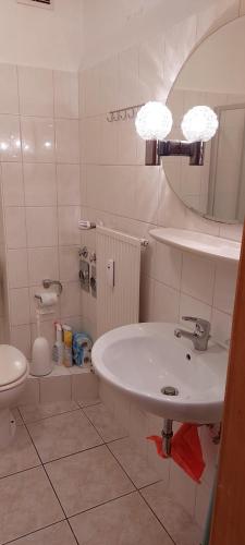 La salle de bains est pourvue d'un lavabo, de toilettes et d'un miroir. dans l'établissement Ferienwohnung Julechka, à Bremerhaven