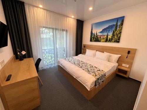 ein Schlafzimmer mit einem Bett und einem großen Fenster in der Unterkunft HELIOS Boutique Hotel in Săcele