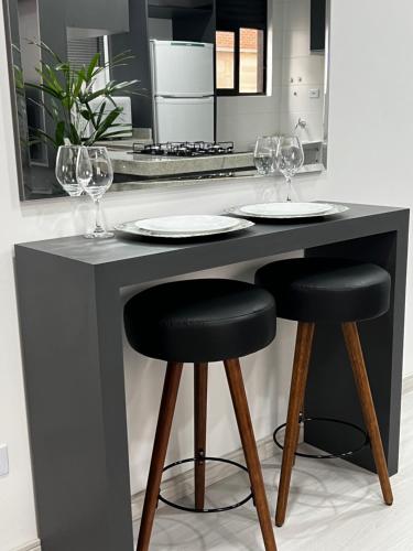 a kitchen with a counter with two plates and wine glasses at Lindo apartamento in Curitiba