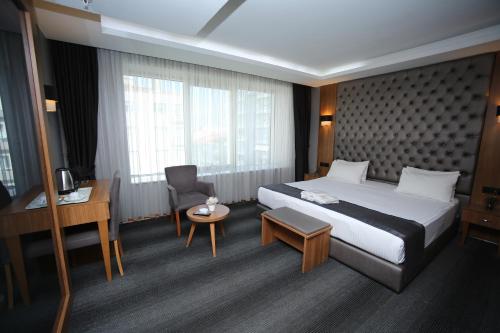 アンカラにあるGrand Silay Hotelの大きなベッドとデスクが備わるホテルルームです。