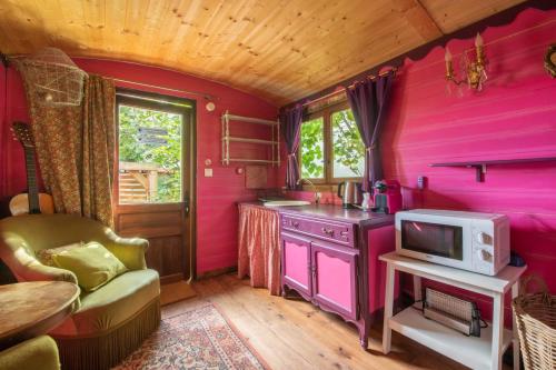 um quarto com uma cozinha cor-de-rosa e uma televisão em Roulotte Insolite avec terrasse proche Paris em Noisy-le-Grand