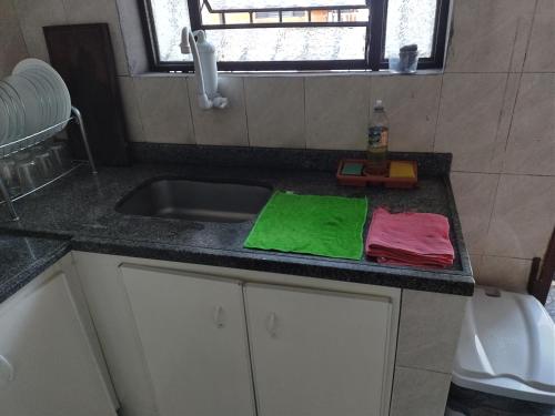 una encimera de cocina con toallas verdes y rosas. en Quartos econômicos, en Manaus