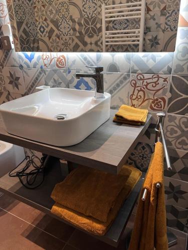 a bathroom with a sink and towels on a shelf at Minardi Apartments in Vercelli
