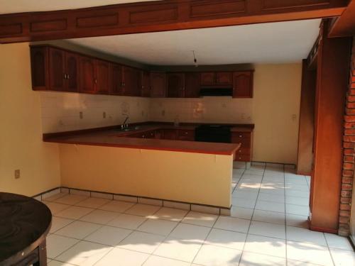 an empty kitchen with wooden cabinets and a sink at CASA GRANDE HERMOSA in Erongarícuaro